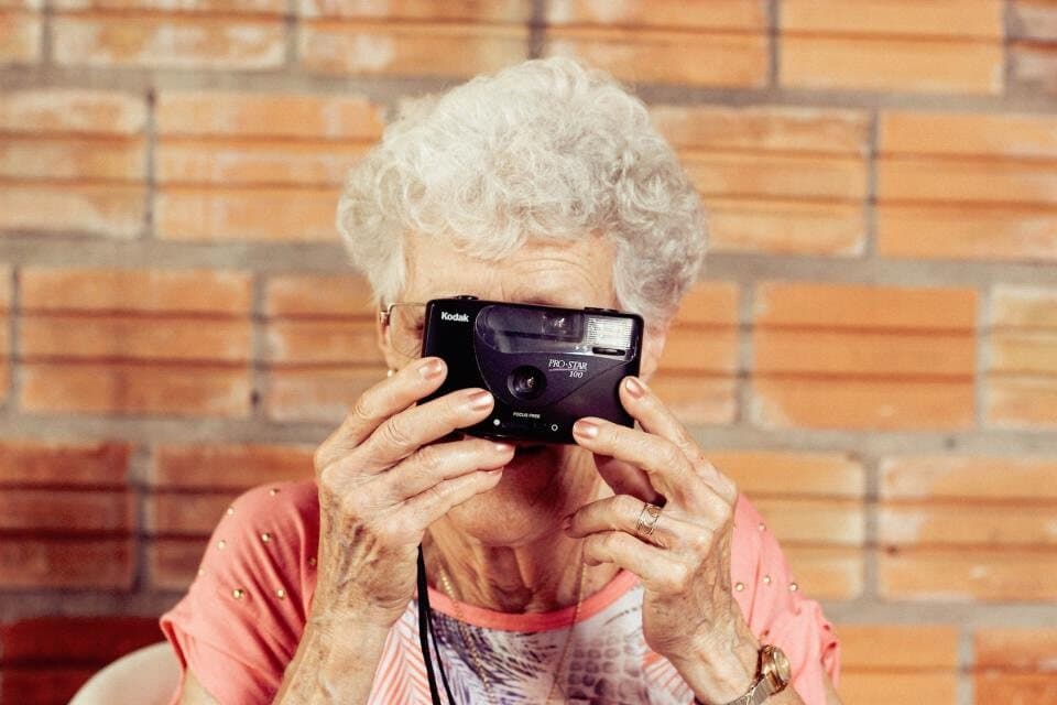 Uma senhora idosa a tirar uma fotografia com uma máquina antiga